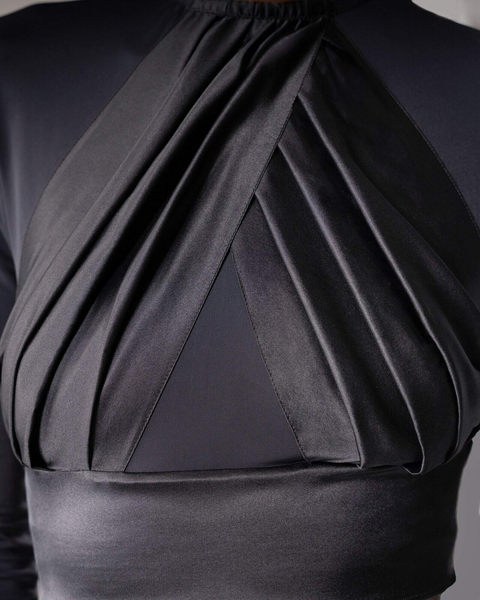 Zoom sur le drapé de satin de soie qui habille la poitrine féminine.