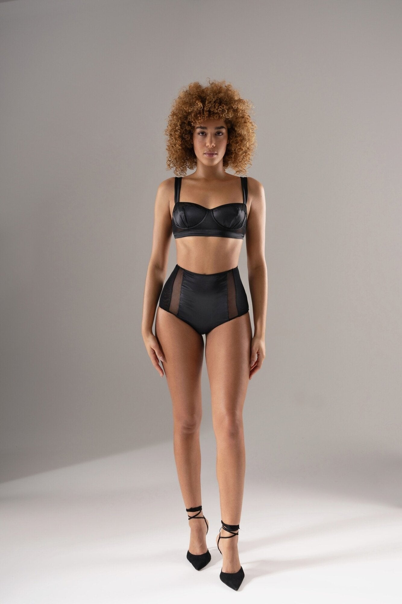 Femme de face portant le shorty 04.17 en soie noire et tulle transparent, coupe taille haute, ambiance studio lumineux.