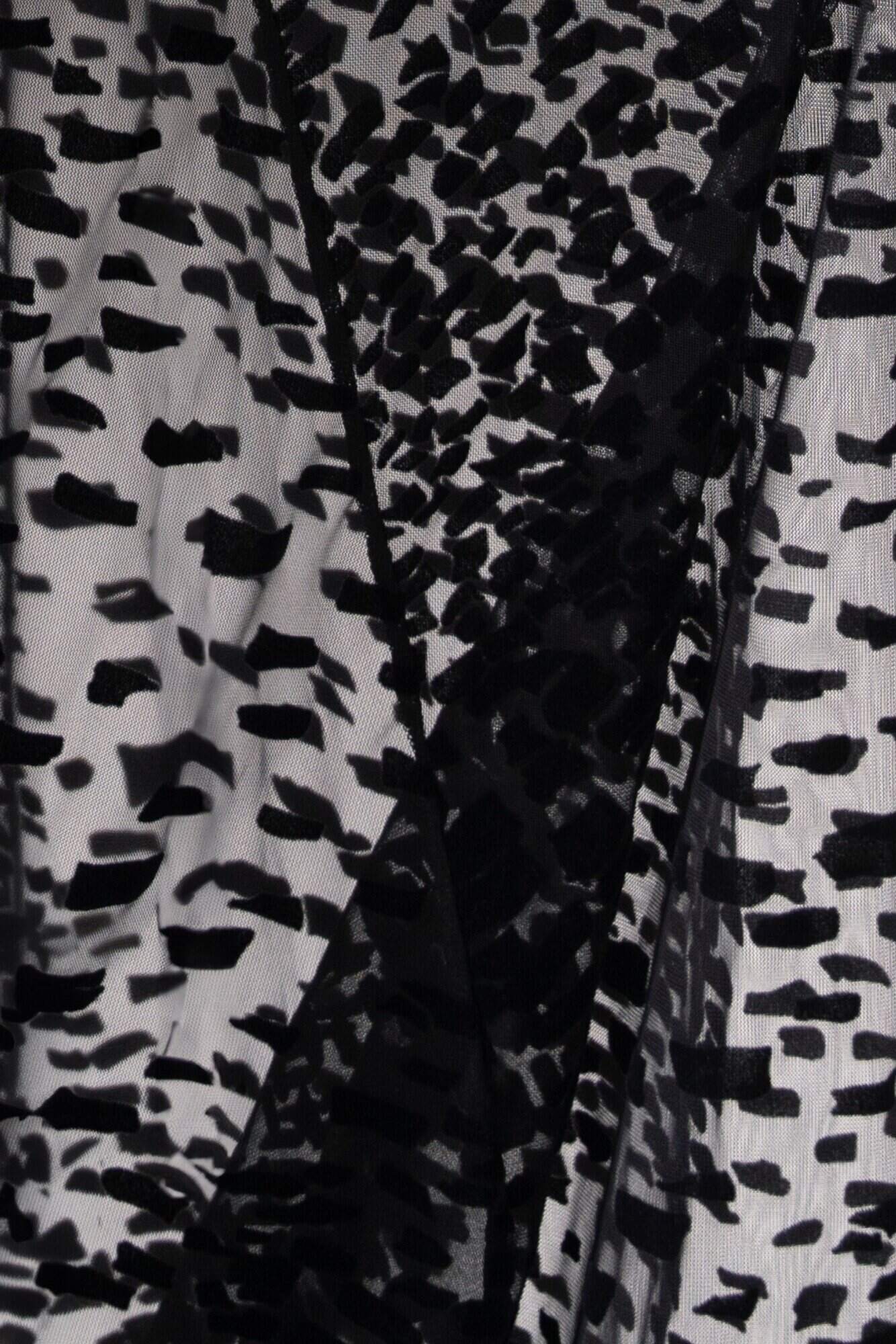 Gros plan sur le tulle noir floqué velours du kimono Lumey, texture semi-transparente à motifs graphiques à l'allure d'un imprimé léopoard géométrique