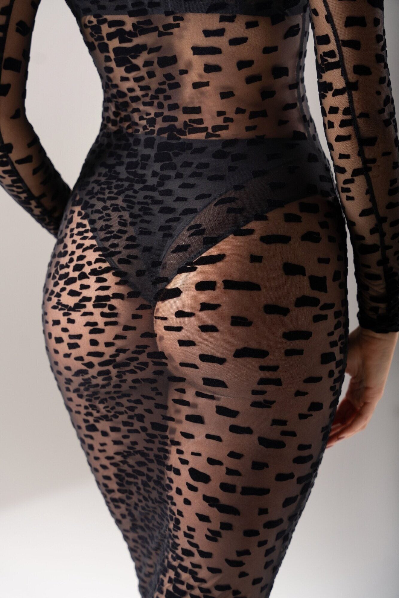 Gros plan sur le dos de la robe 11.14 en tulle floqué transparent, laissant apparaître la culotte 03.12 à la coupe tanga et les détails du motif texturé.