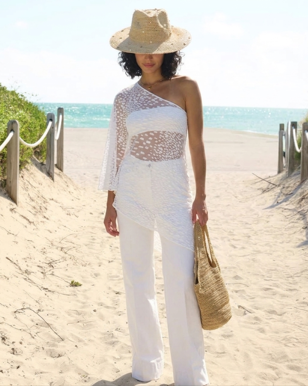 Lumey Paris white asymmetric top in velvet flocked tulle, worn over white trousers at the beach