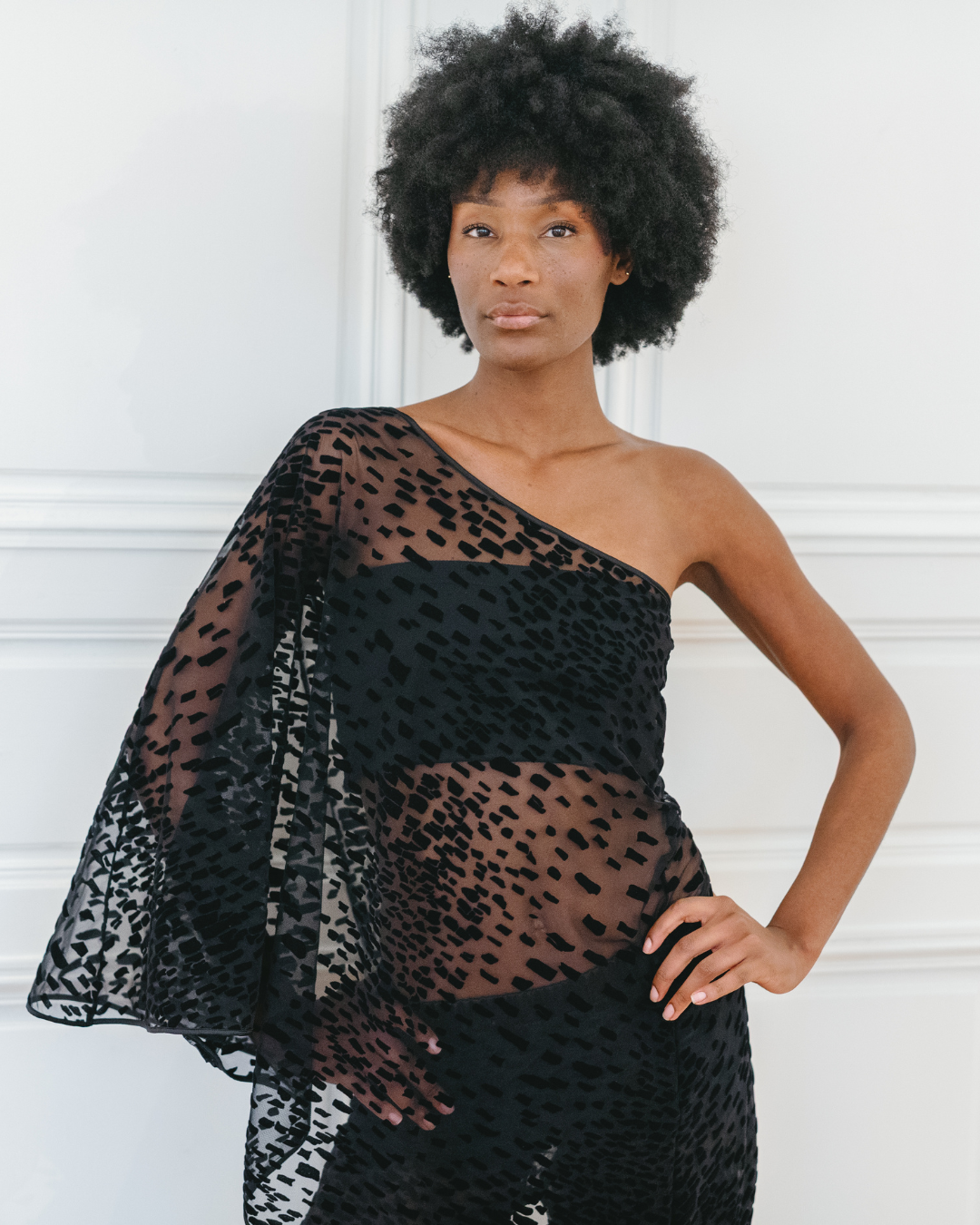 Close-up of the Lumey Paris 11.14 black asymmetric cape top — velvet flocked tulle, one-shoulder neckline, silk satin trims at neckline and hem