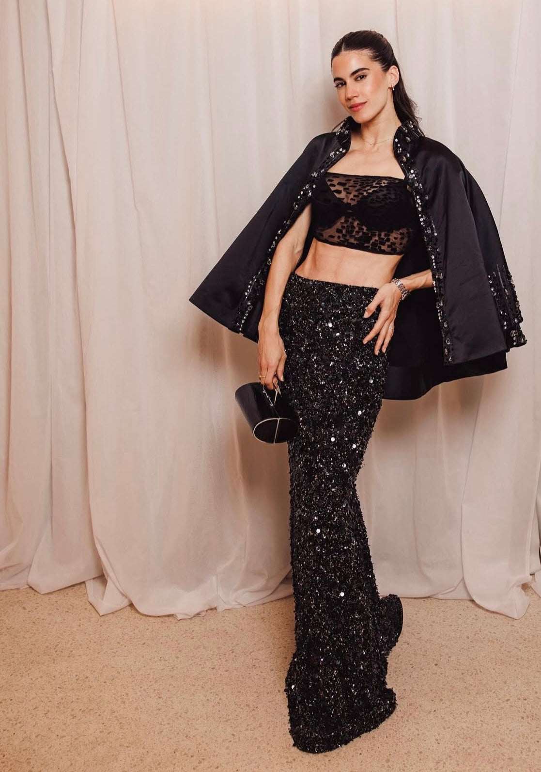 Natacha Eguia wearing the Lumey Paris sheer black velvet-flocked tulle Bra 11.14 styled with a sequined skirt and cape for an evening look, French luxury ready-to-wear