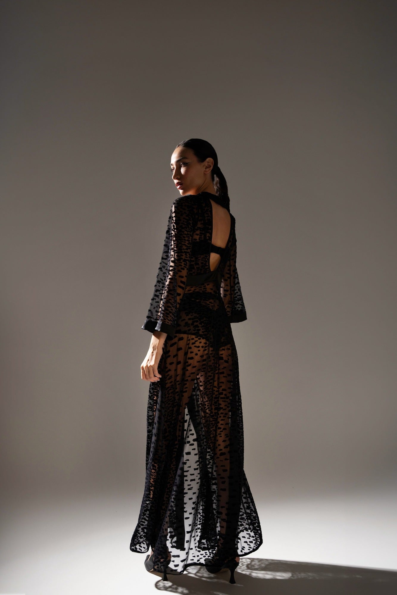 Studio back view of the ankle-length black kimono, highlighting the deep open back cut and sheer transparency.
