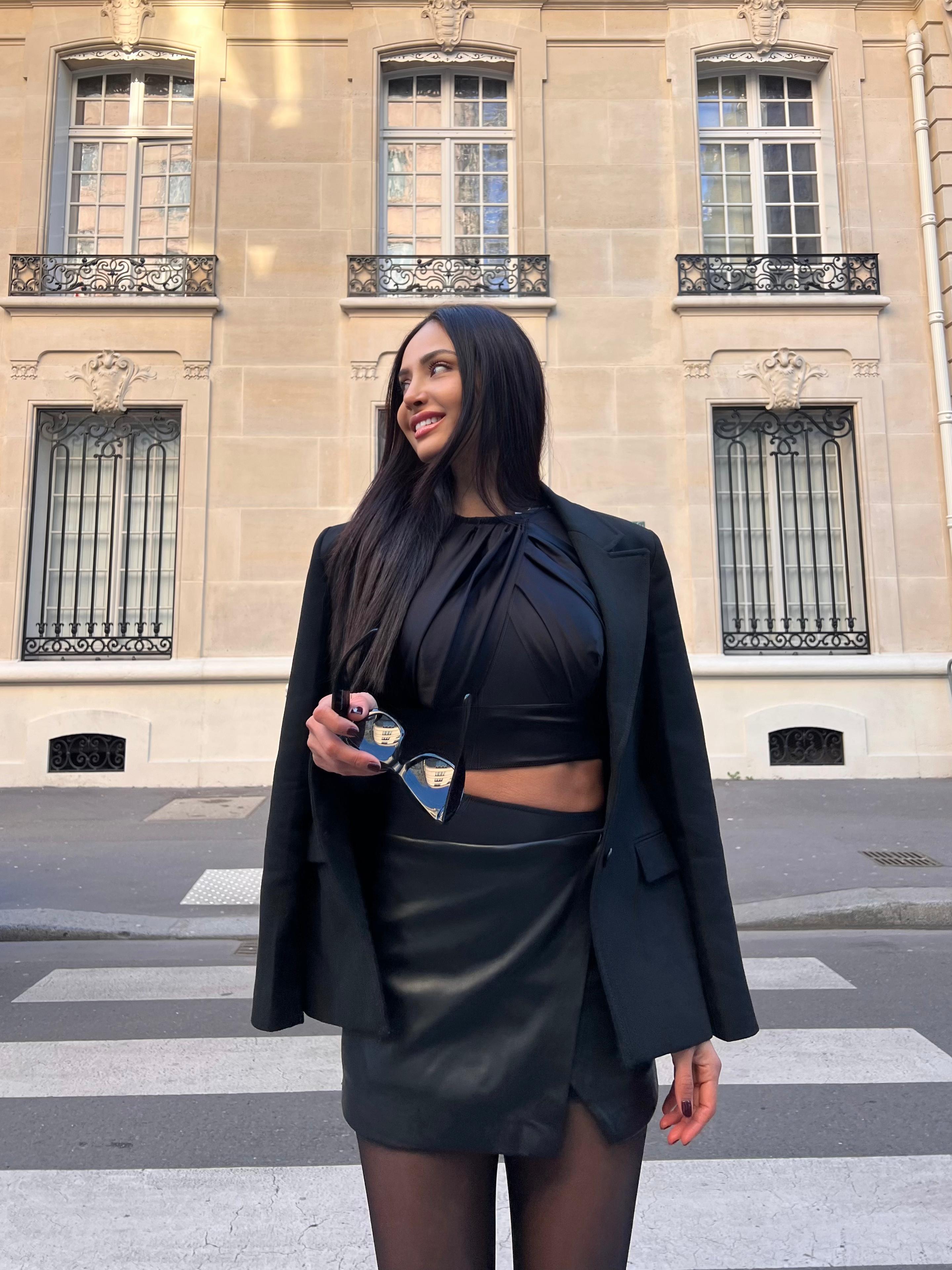 Patricia Contreras in the Lumey Paris 02.08 black long-sleeve bodysuit with cut-out waist, street style Paris, Haussmann architecture backdrop